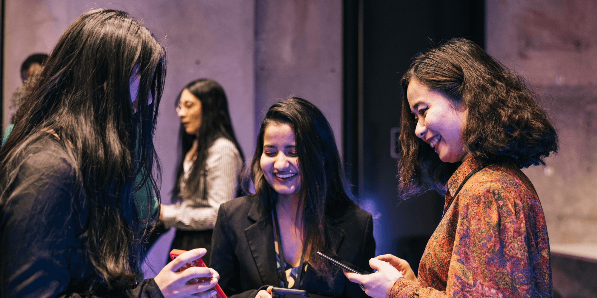 Three women at an event with mobile phones