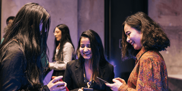 Three women at an event with mobile phones